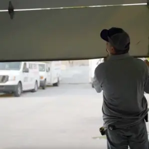 Technician lifting a garage door while working on residential garage door repair.