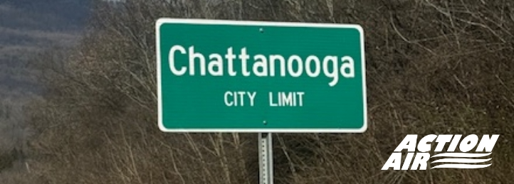 Chattanooga city limit sign on roadside with trees and hills in the background.